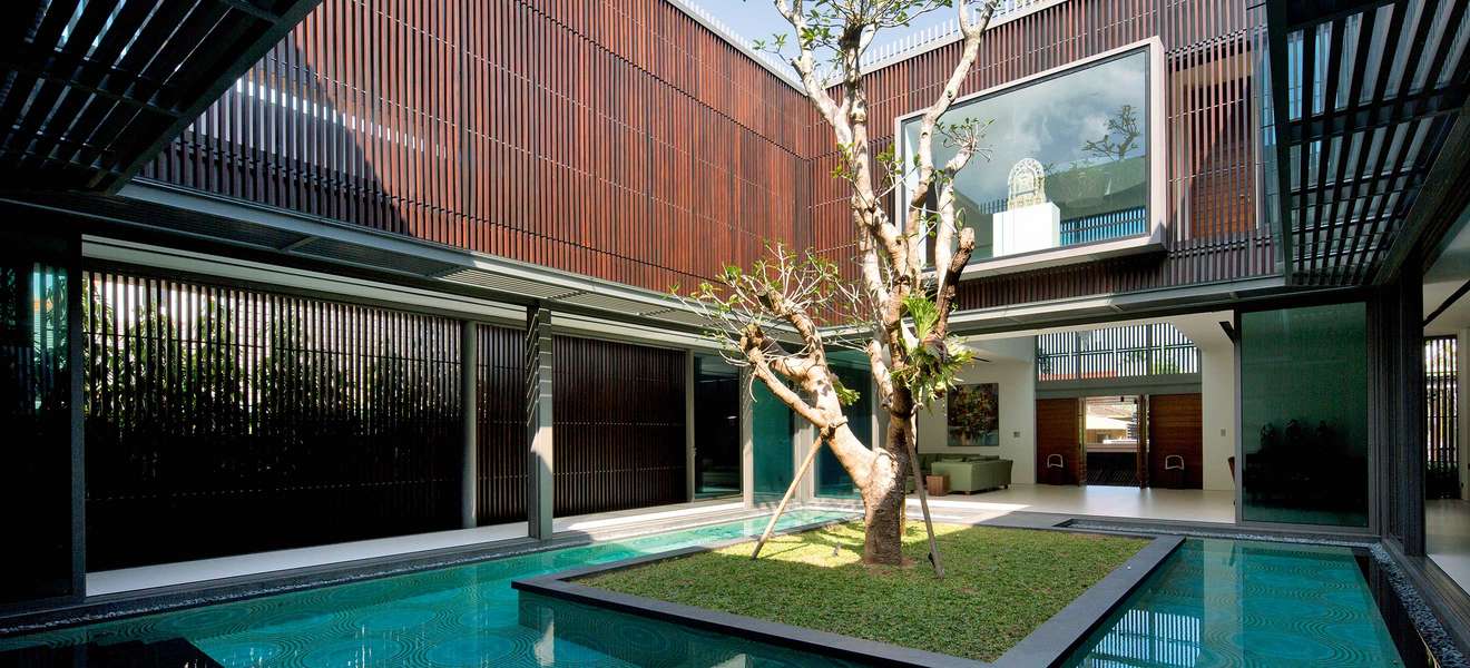 Ein alter Baum markiert den Mittelpunkt des Patios im Centennial Tree House von Wallflower Architecture + Design an der Ostküste Singapurs, der von traditionellen chinesischen Hofhäusern inspiriert ist. 