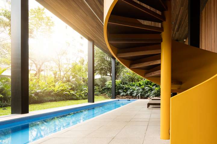 Isay Weinfeld platzierte einen lang gestreckten Pool unter dem Vordach eines mehrstöckigen Wohngebäudes inmitten der brasilianischen Metropole São Paulo.